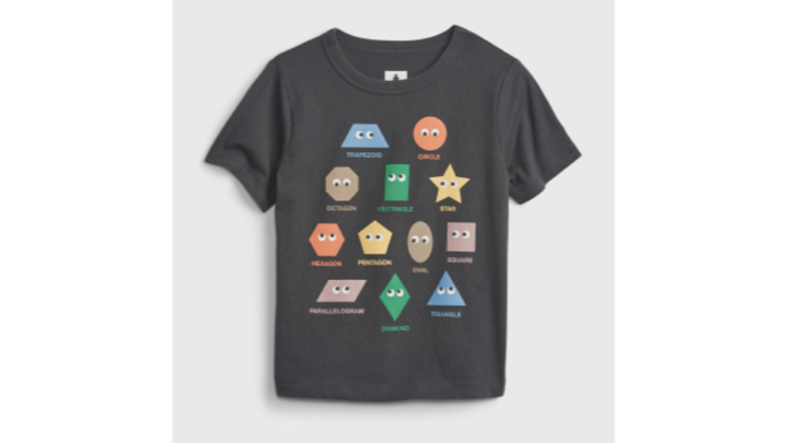 A T-shirt for toddlers with 12 geometric shapes in various colors and with googly eyes. Each shape has a name underneath, which are—from top to bottom and left to right: trapezoid, circle, octagon, rectangle, star, hexagon, pentagon, oval, square, parallelogram, diamond, and triangle.