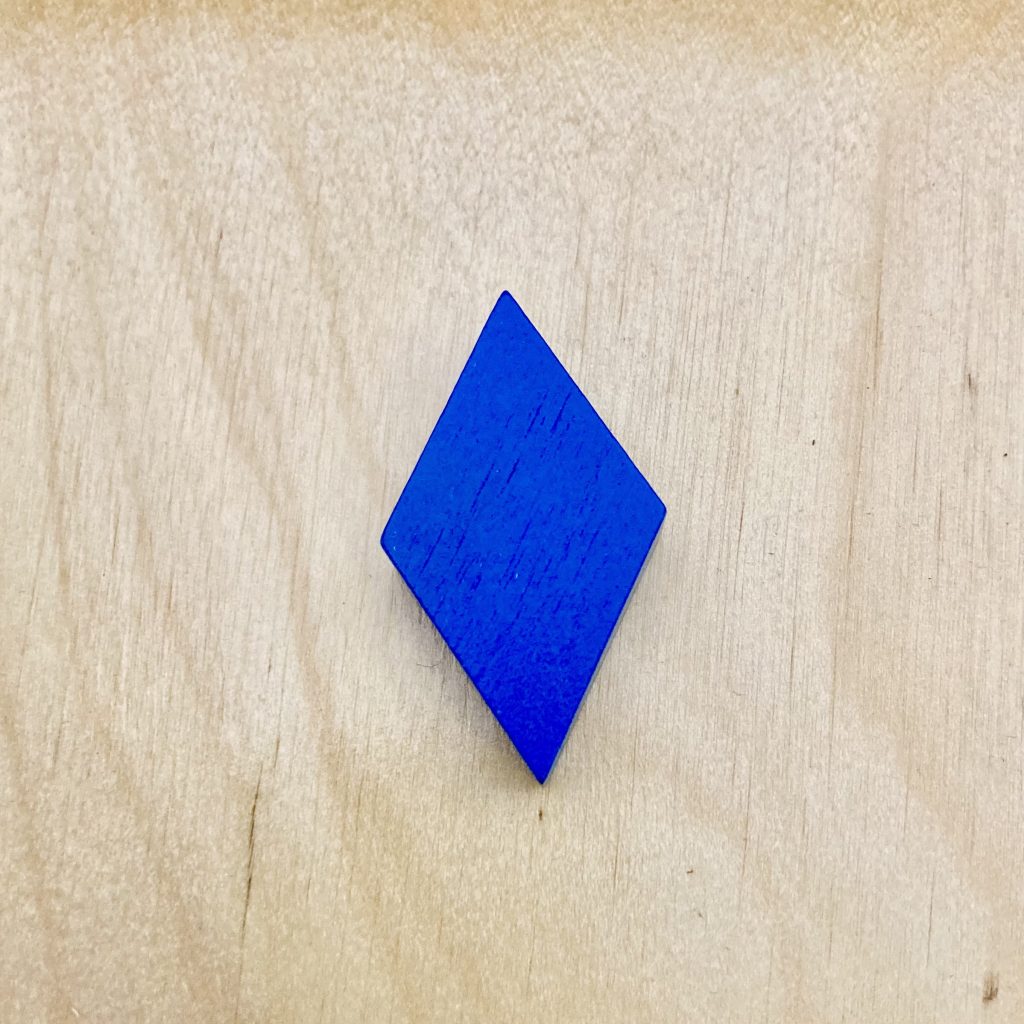 A blue diamond/rhombus pattern block on a wooden tabletop.