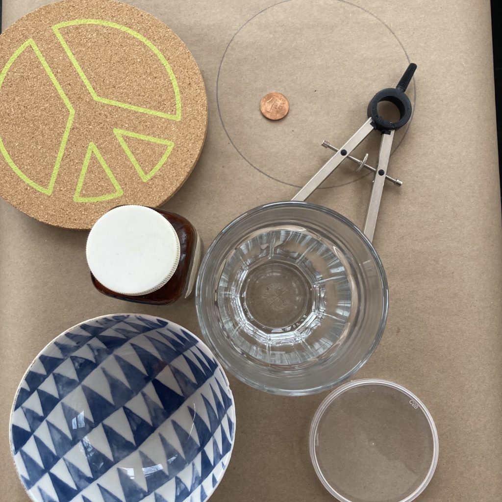 A collection of circular real-world objects, including a drinking glass, a penny, a bowl, a corkboard, and a compass (for drawing circles)