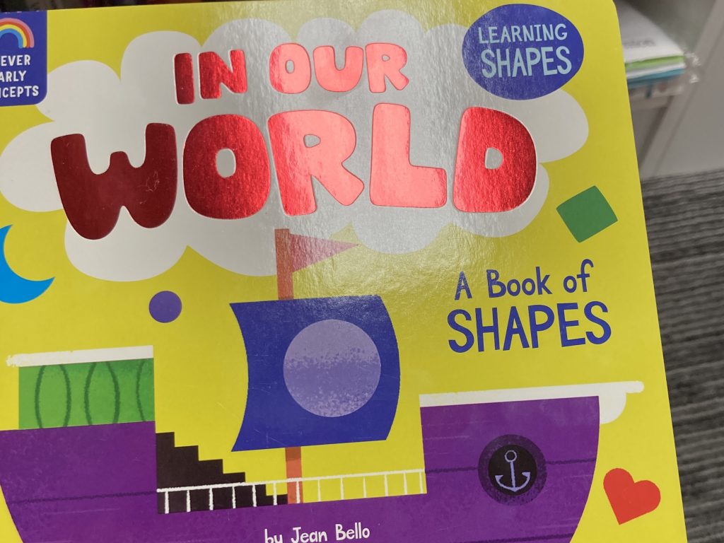 A colorful board book titled "In Our World: A Book of Shapes"